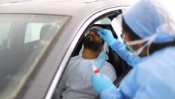 Члени медичного персоналу беруть мазок у чоловіка під час тестування «проїздом» в Абу-Дабі, Об'єднані Арабські Емірати