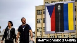 Banner pe o clădire din capitala cehă îl arată pe președintele rus Vladimir Putin, între steagurile ceh și ucrainean. Praga, 28 octombrie 2022