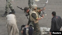 Egypt -- A member of the press lies on the ground after being attacked by mobs while soldiers surround him in Cairo, 03Feb2011