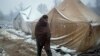 BOSNIA-HERZEGOVINA -- A migrant walks amid tents during snowfall at the Vucjak refugee camp outside Bihac, December 2, 2019