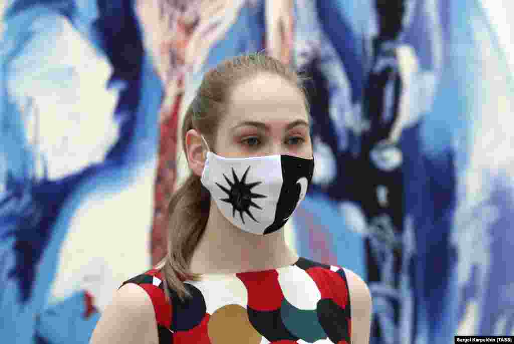 A woman stands in front of a work by American artist Donna Huanca.