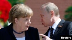 Russian President Vladimir Putin (right) speaks with German Chancellor Angela Merkel as they attend a wreath-laying ceremony at the Tomb of the Unknown Soldier by the Kremlin walls in Moscow on May 10.