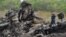 Responders stand amid aircraft parts at the crash site one day after Malaysia Airlines Flight MH17 crashed on July 19, with 298 people from 11 countries aboard, in a field near the town of Shaktarsk, in rebel-held eastern Ukraine.