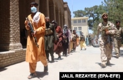 Some of around 500 residents of the Guzara region who have taken up arms to fight the Taliban walk with Afghan soldiers on June 23.