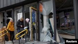 Employees check medicines at a damaged pharmacy near a metro station that was hit during a Russian missile strike on Kyiv overnight on October 19.