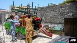 Afghan refugees load their belongings onto a truck in Peshawar, Pakistan, on July 13 as they prepare to depart for Afghanistan.