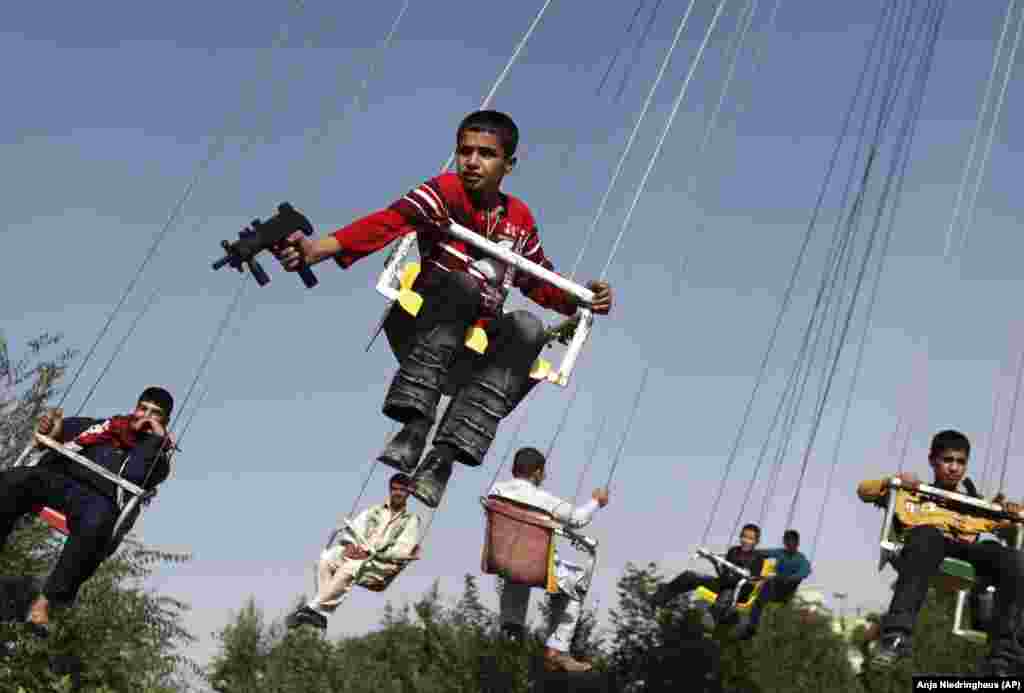 An Afghan boy holding a toy gun as he enjoys a ride on a merry-go-round to celebrate the Eid al-Fitr festival in Kabul, September 20, 2009.