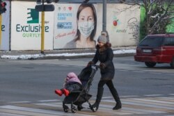 Женщина с детской коляской переходит дорогу в Алматы.