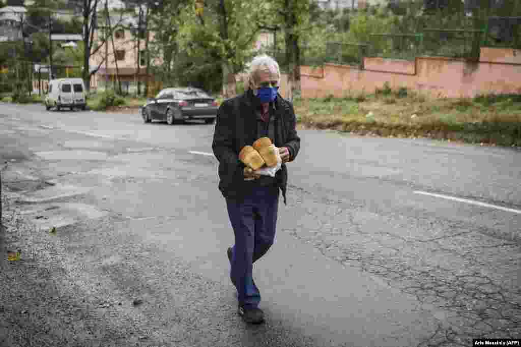 A masked man walks home after picking up free loaves of bread. In addition to the ongoing conflict over Nagorno-Karabakh, Armenia and Azerbaijan are struggling with a resurgence of COVID-19.