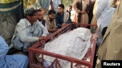 Relatives sit beside the body of a female polio vaccinator who was killed by unidentified gunman in Chaman on April 25.