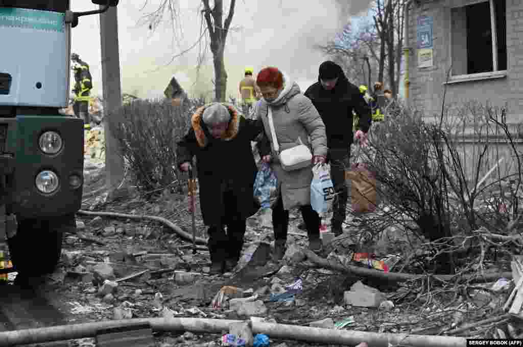 Мешканці будинку у Харкові, в який вдарила російська балістична ракета, йдуть, несучи в руках вцілілі речі. Харків, 7 березня 2026 року