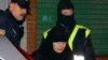 Masked members of Spanish security forces escort a veiled woman arrested early on 10 January 2006