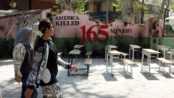 Iranian women walk past a symbolic Minab school, referring to the school targeted in a February air strike that killed 120 schoolchildren, in Tehran in April. 