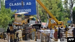 A crane removes damaged vehicles at the site of a suicide bomb attack outside the northwestern Pakistani town of Fateh Jang on June 4, 2014.