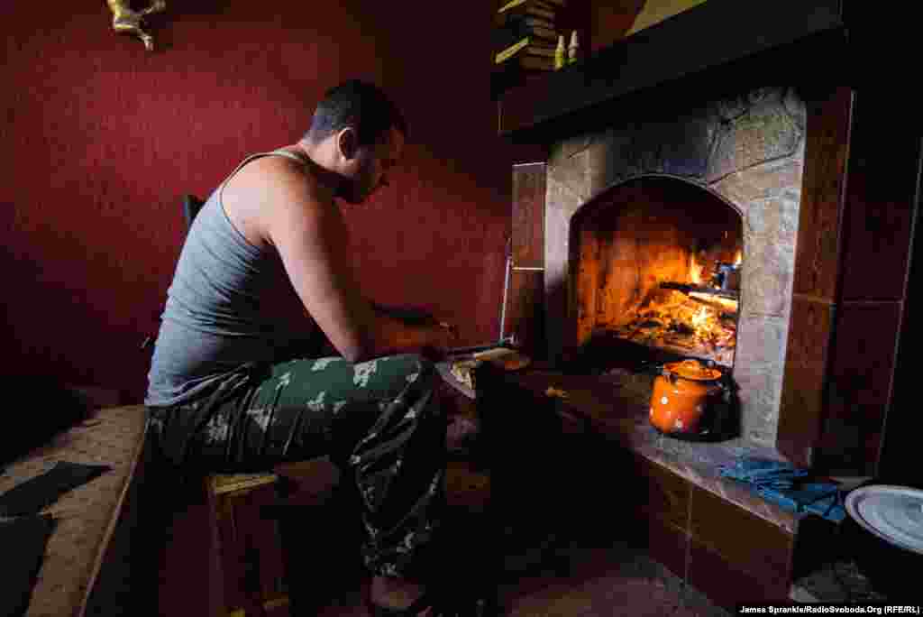 A soldier of the 93rd Brigade cooks his meal in a fireplace. Most of the soldiers don&rsquo;t come from wealthy backgrounds themselves and enjoy living in expensive dwellings -- even if they&#39;re partly destroyed.