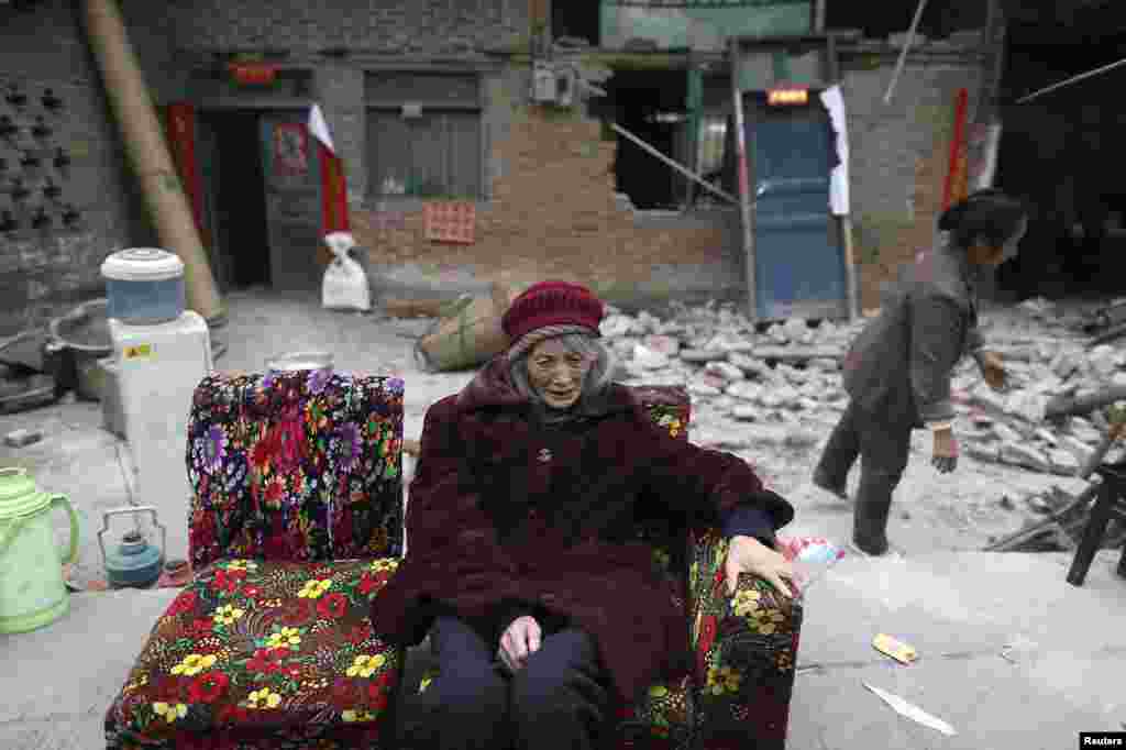 An elderly woman sits on a sofa in front of damaged houses in Taiping following the deadly April 20 earthquake in China&#39;s Sichuan Province. (Reuters)