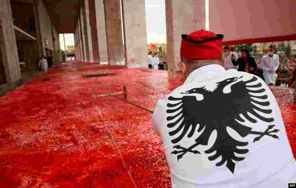 A chef cuts a huge cake, with the Albanian flag symbols, measuring 550 square meters, on the main boulevard of Tirana, Albania, during centenary celebrations on November 28. (AFP/Gent Shkullaku)