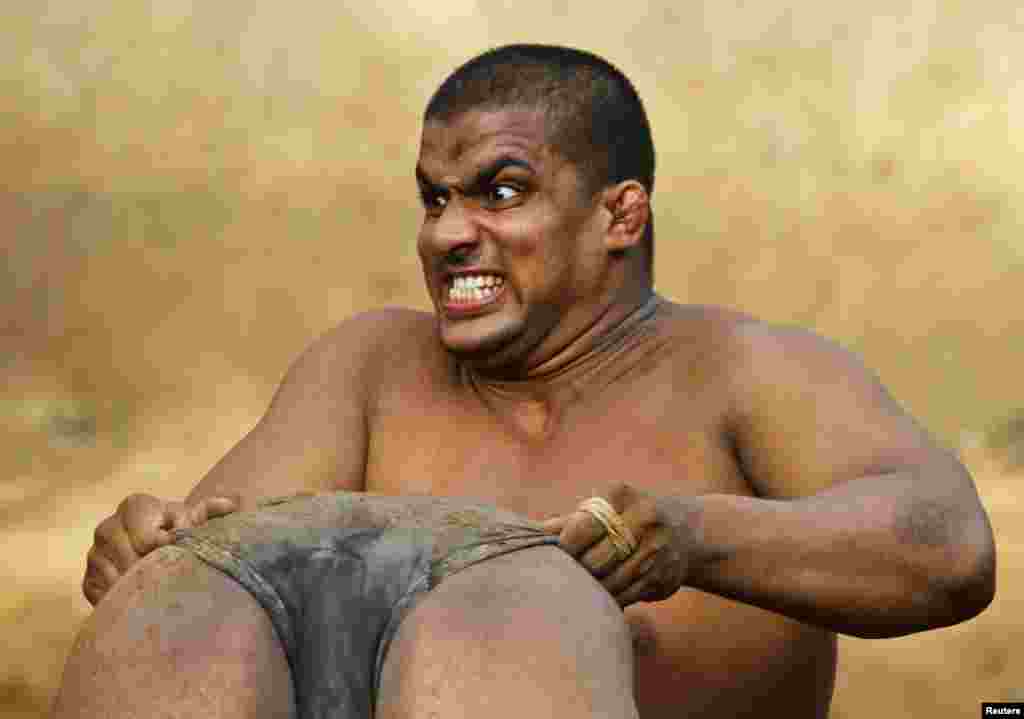 A wrestler reacts as he lifts his colleague in the mud at an Indian Kushti mud-wrestling training center on the outskirts of New Delhi on June 13. Kushti is a traditional sport in India but more and more young athletes are now training on mats instead of mud to gain access to top international competitions like the Olympic and Commonwealth games. (Reuters/Parivartan Sharma)