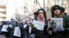People hold posters with names of the people killed in the Ukraine International Airlines plane that was shot down in Iran in January during a commemoration ceremony in front of the Iranian Embassy in Kyiv on February 17.