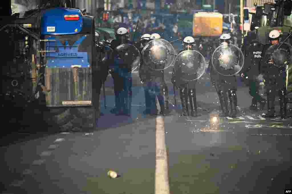 Ofițerii de poliție stau lângă tractoarele manifestanților în apropierea Parlamentului European.