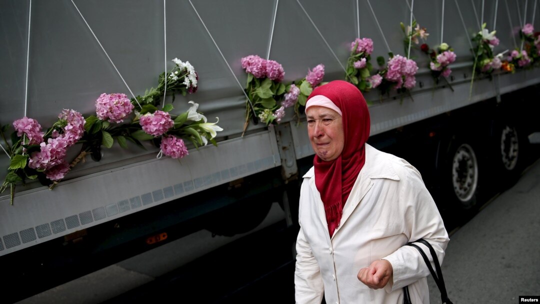 A woman cries near a truck carrying coffins of newly identified victims of the 1995 Srebrenica massacre, in Sarajevo, July 9, 2015.