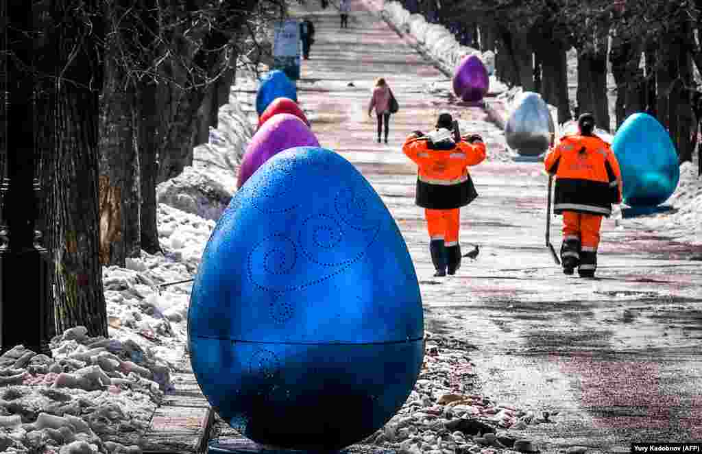 Municipal workers walk past giant Easter egg decorations set up in the center of Moscow. (AFP/Yuri Kadobnov)