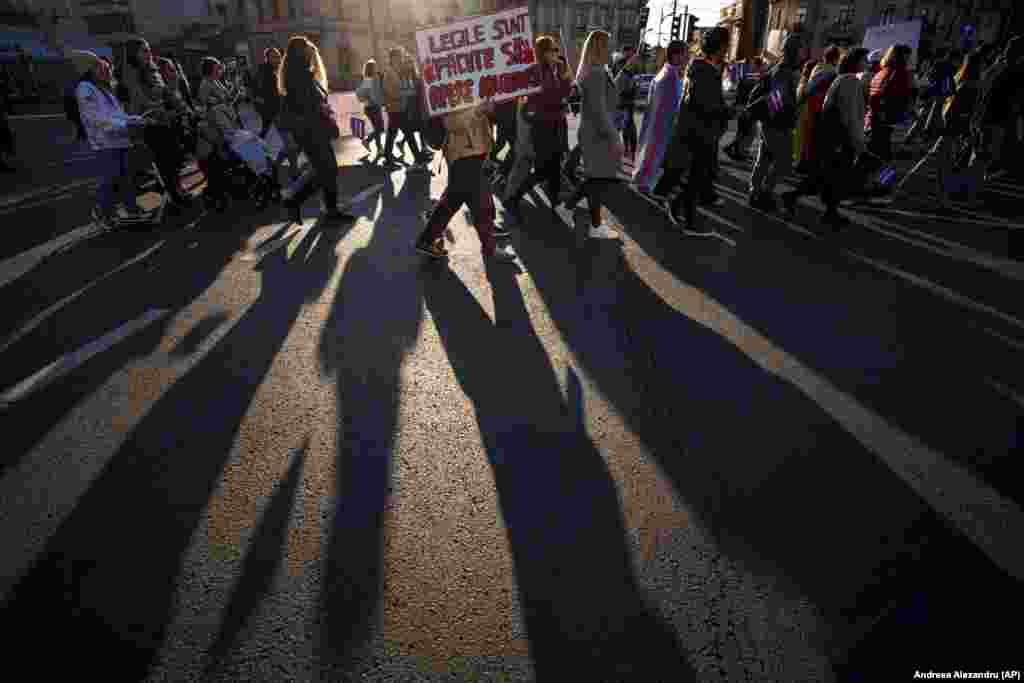 People march holding banners reading &quot;The Laws Are Made To Protect The Abusers&quot; during a protest aimed at raising awareness of the violence and prejudice against women in Romanian society in Bucharest.