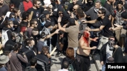 A man covered in his own blood tries to escape after a group of leftist protesters attacked him during a demonstration against austerity measures in Athens. (file photo)