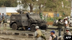 Italian and U.S. soldiers inspect the site of a blast that struck vehicles with the NATO-led force in Kabul, killing at least 16 people.