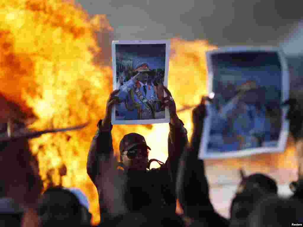 Men hold up posters of Libyan leader Muammar Qaddafi as a fuel truck burns in Tripoli on March 2. Photo by Chris Helgren for Reuters