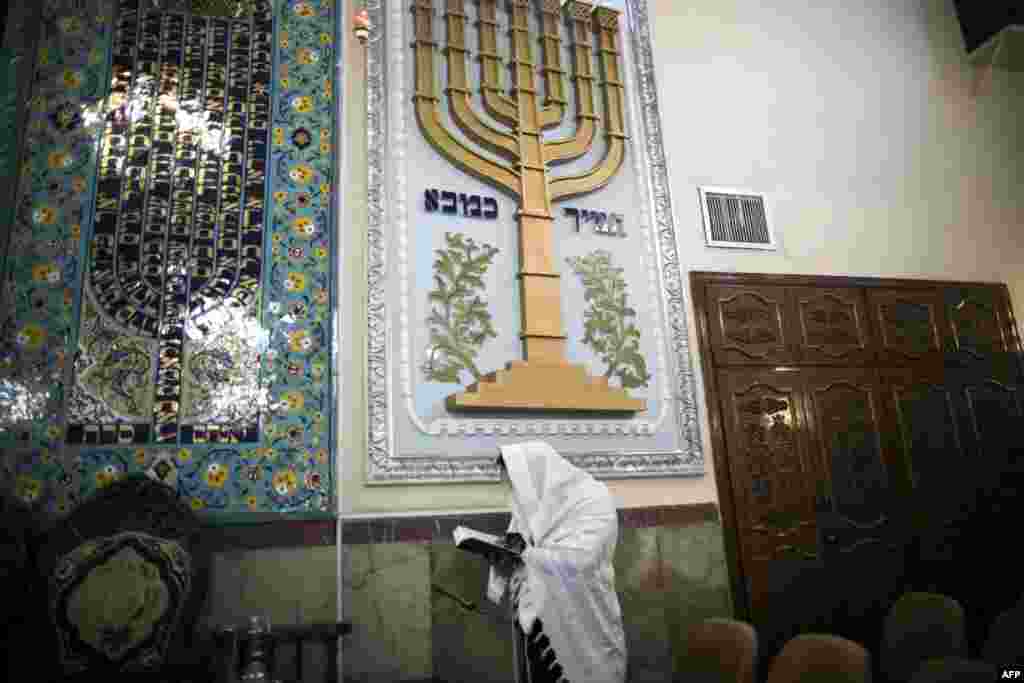 An Iranian Jewish man wearing a Tallit reads the Torah during morning prayers at the Yussef Abad Synagogue in Tehran.