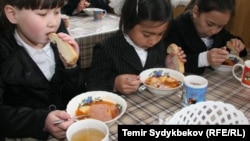 Башталгыч класстын окуучулары түшкү тамак ичип жаткан учуру. Бишкек. Иллюстрациялык сүрөт.