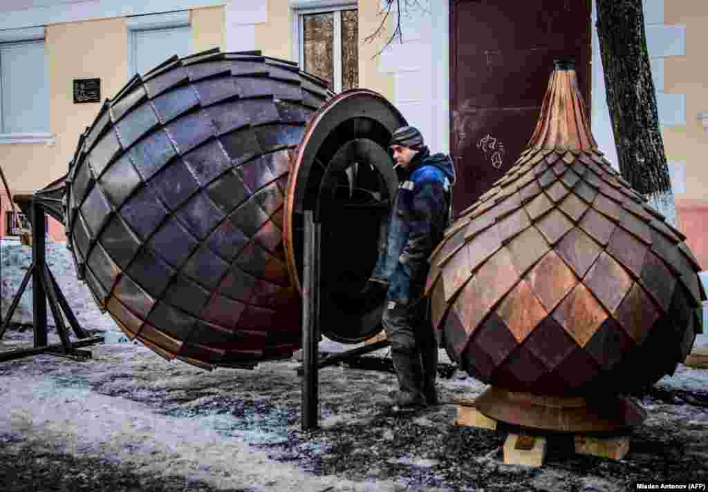 A worker stands next to two metal onion domes during the renovation of a church in the historical center of Yaroslavl, Russia. (AFP/Mladen Antonov)