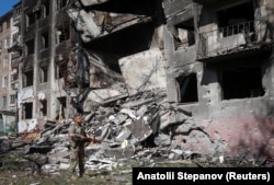A member of the White Angels holds a shotgun as he checks for remainig residents in a damaged building in Druzhkivka on June 22.