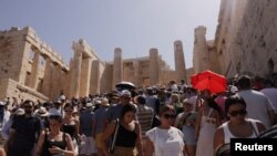 Turiștii vizitează Acropola din Atena în timpul unui val de căldură care afectează Grecia.