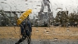 A woman with a protective face mask walking past the Eiffel tower is pictured through rain drops on a car window at Trocadero square in Paris during a lockdown imposed to slow the spread of the coronavirus disease (COVID-19) in France