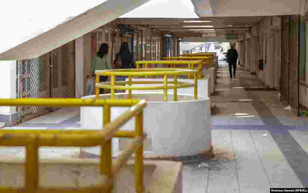 Disa qytetarë duke kaluar në një nga korridoret e ndërtesës, ku ka disa dyqane. 