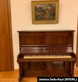 Një piano dhe një pikturë shihen në një nga hapësirat e vilës.