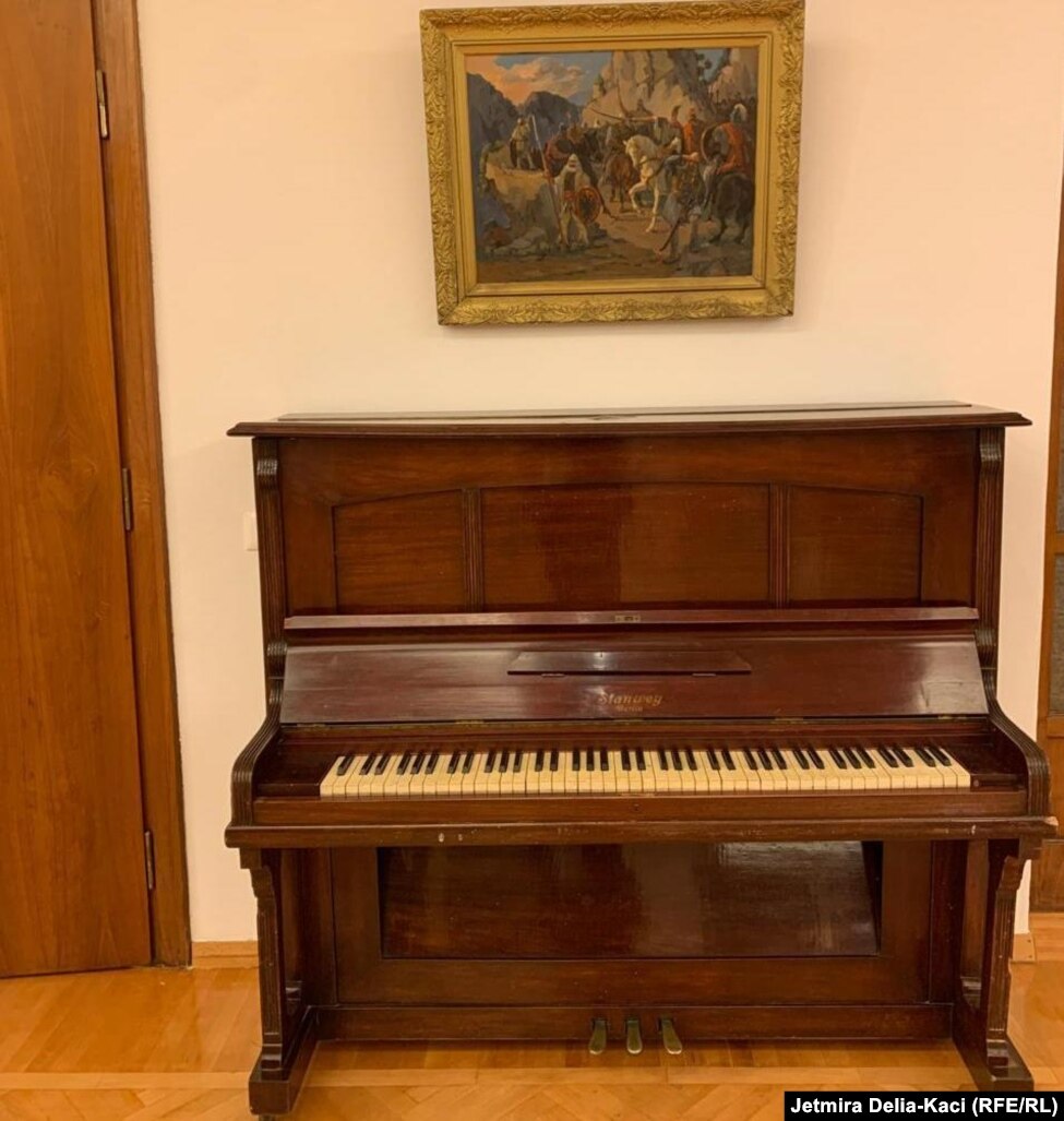 Një piano dhe një pikturë shihen në një nga hapësirat e vilës.