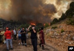 Oamenii din localitatea Sirtkoy, aflați în fugă din calea incendiilor ce au devastat sud-vestul turciei. Ministrul agriculturii și pădurilor din Turcia, Bekir Pakdemirli, a scris duminică, 1 august, pe Twitter că 5 incendii continuă să mistuie zonele turistice din Antalya și Mugla.