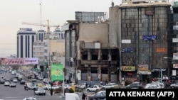 Vehicles drive past a burned-out building destroyed during the unrest in the Tehran on January 19.
