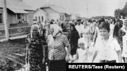 Persoanele evacuate din fermele colective din regiunea Cernobîl se plimbă pe străzile unui sat nou construit din raionul Makarovsky, lângă Kiev, pe 4 august 1986.