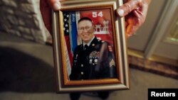 Wilburn Russell, 73, displays a portrait of his son, John M. Russell, the Army sergeant who was convicted of killing five fellow soldiers.