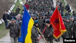 Українські вояки із прапорами і виконанням державного Гімну України на підході до російських військових, які відкрили попереджувальний вогонь. Бельбек, 4 березня 2014 року 