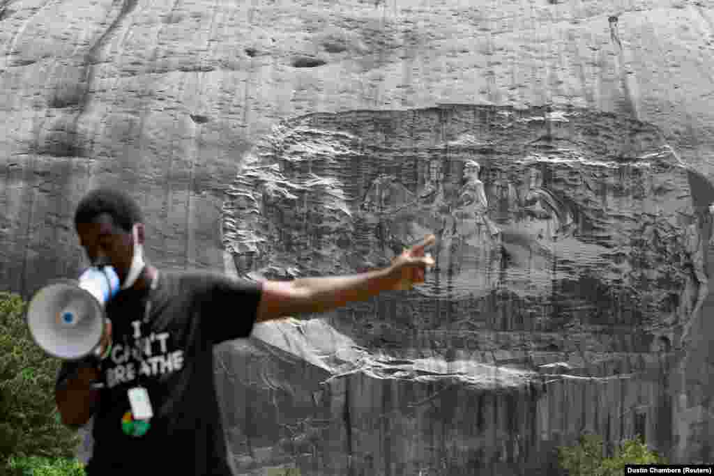 A man speaks into a bullhorn while pointing at the Confederate Monument carved into granite on Stone Mountain while protesting the monument at Stone Mountain Park in Stone Mountain, Georgia, U.S. June 16, 2020.