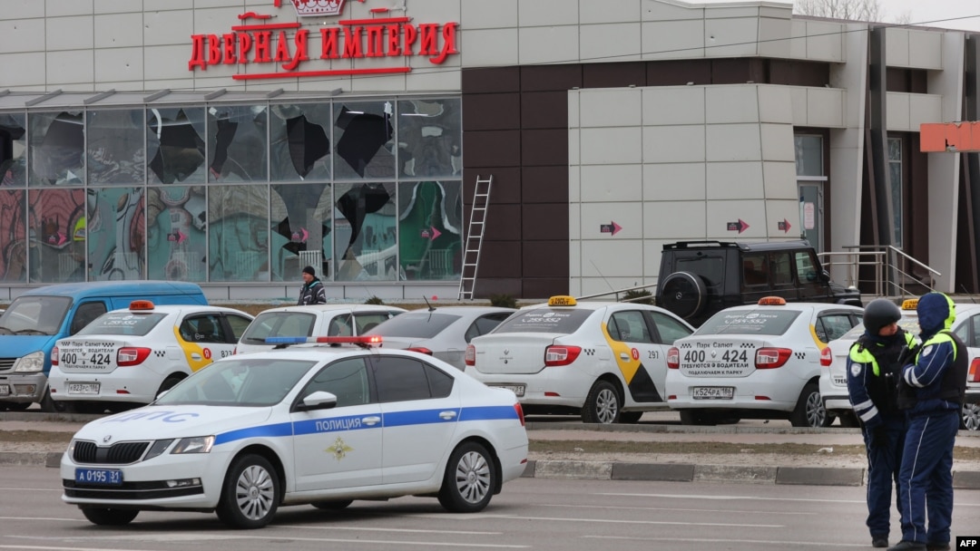 Police officers stand guard in front of a damaged store at the scene of fresh aerial attacks on Belgorod, Russia, on March 14.