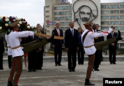 U.S. President Barack Obama (center) and U.S. Secretary of State John Kerry stand near an image of revolutionary hero Camilo Cienfuegos as they watch ceremonial guards during a wreath-laying ceremony at the Jose Marti monument on Revolutionary Square in Havana on March 21.