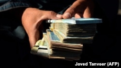 A money changer holds afghani banknotes at a currency exchange market. (file photo)