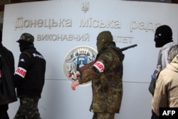 Armed pro-Russians walk outside a government building they seized in mid-April in the eastern Ukrainian city of Donetsk.