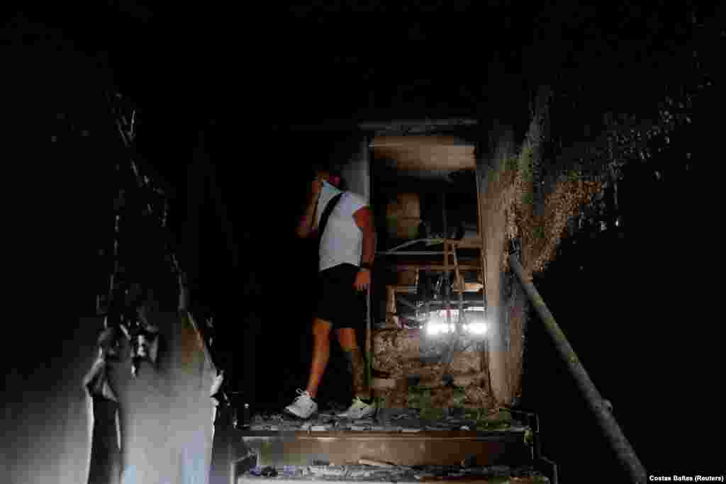 Një burrë duke ecur brenda një shtëpie të djegur, pas një zjarri të egër në periferi të Athinës, në Greqi. (4 gusht)